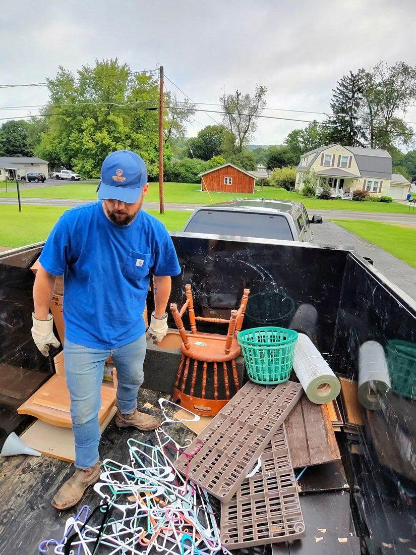 An Iron Valor crew member loading scrap and furniture into the truck bed.